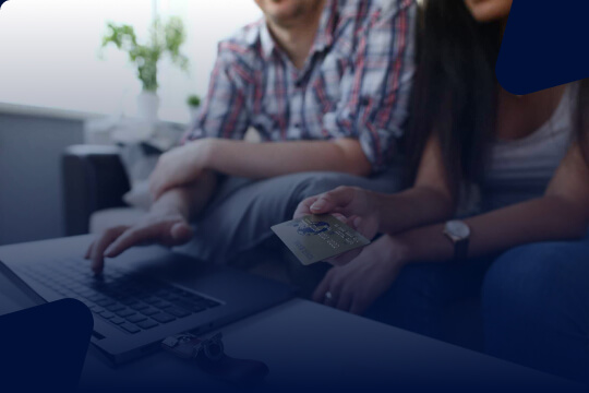 Image of a man and woman in-front of a laptop with a credit card.